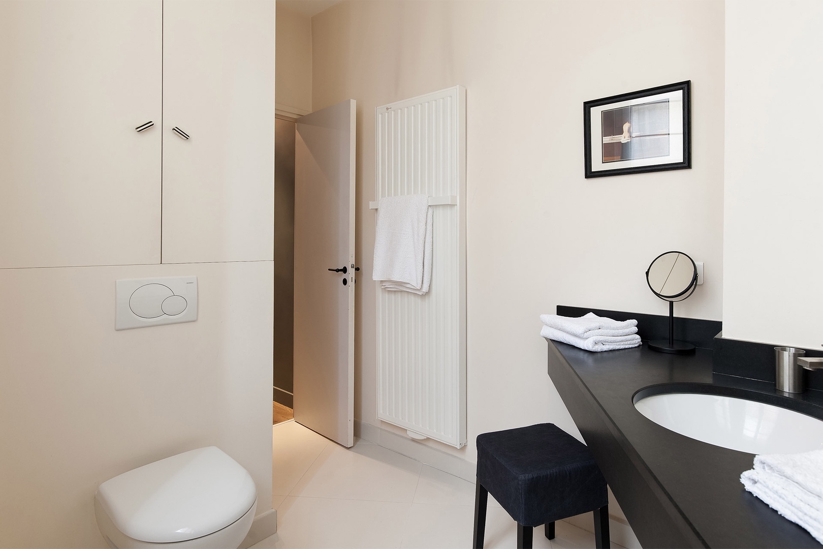 The sink doubles as a vanity with a complementary mirror and seat.