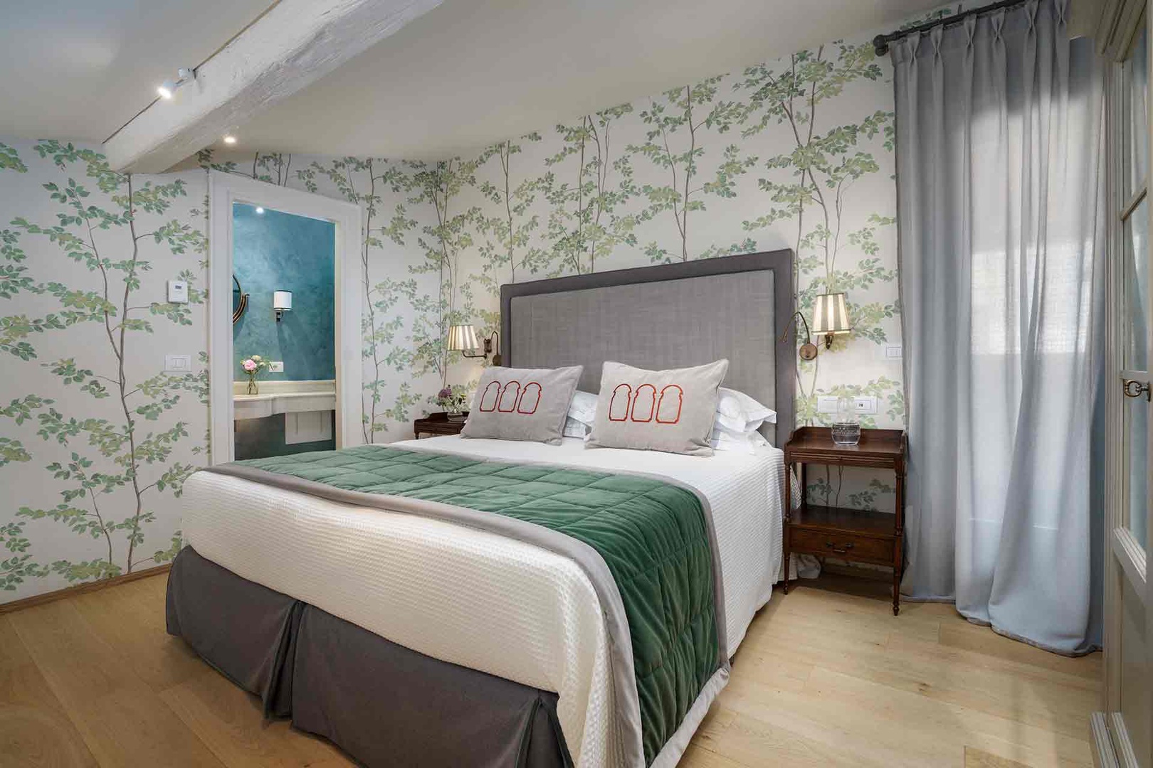 Drift off beneath charming botanical wallpaper and soft linens in Bedroom 1.