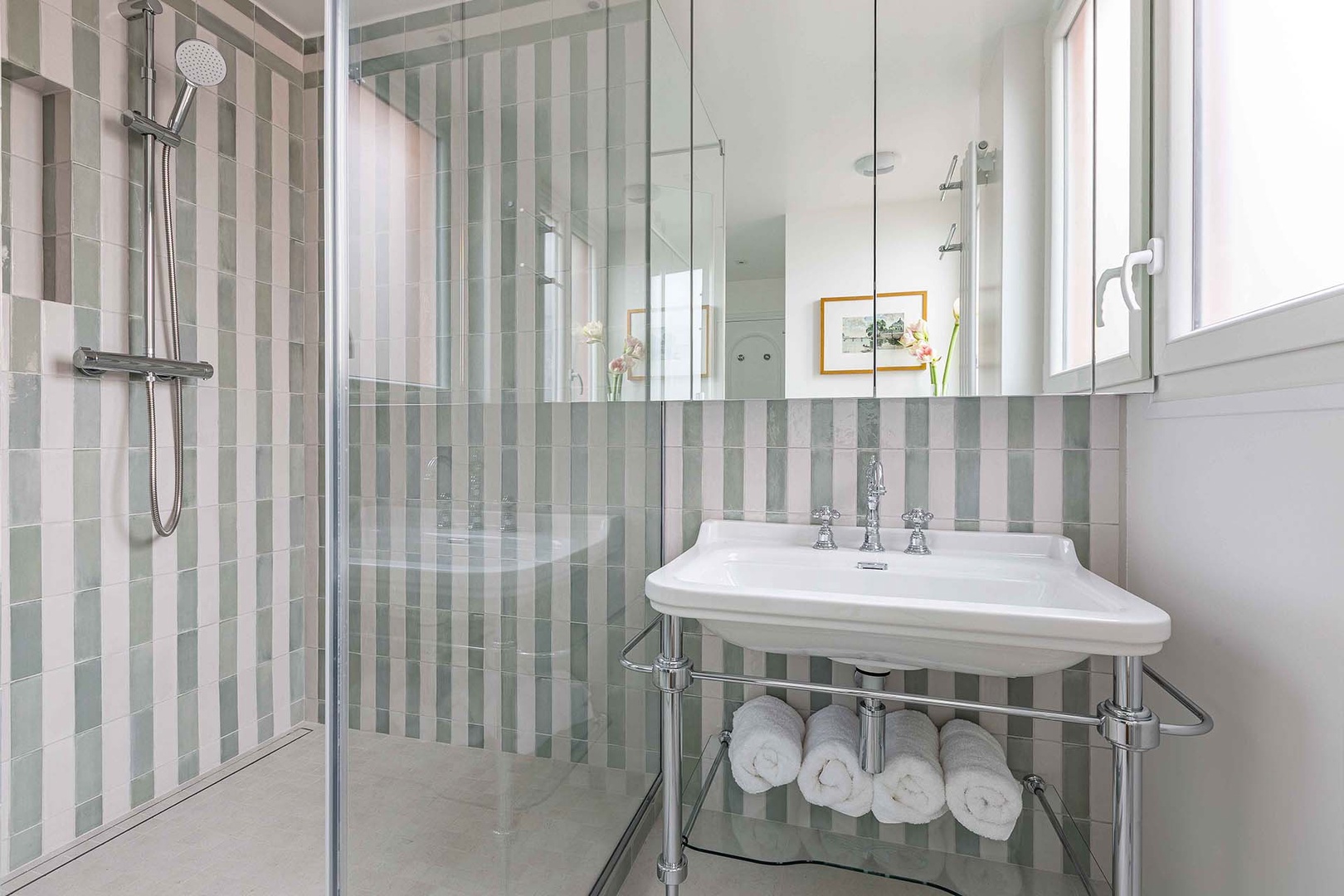 Spacious bathroom with elegant striped tiles, shower, toilet and sink.