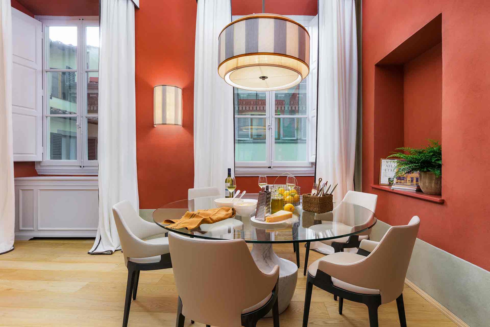 Gather around this elegant glass table beneath warm terracotta walls.