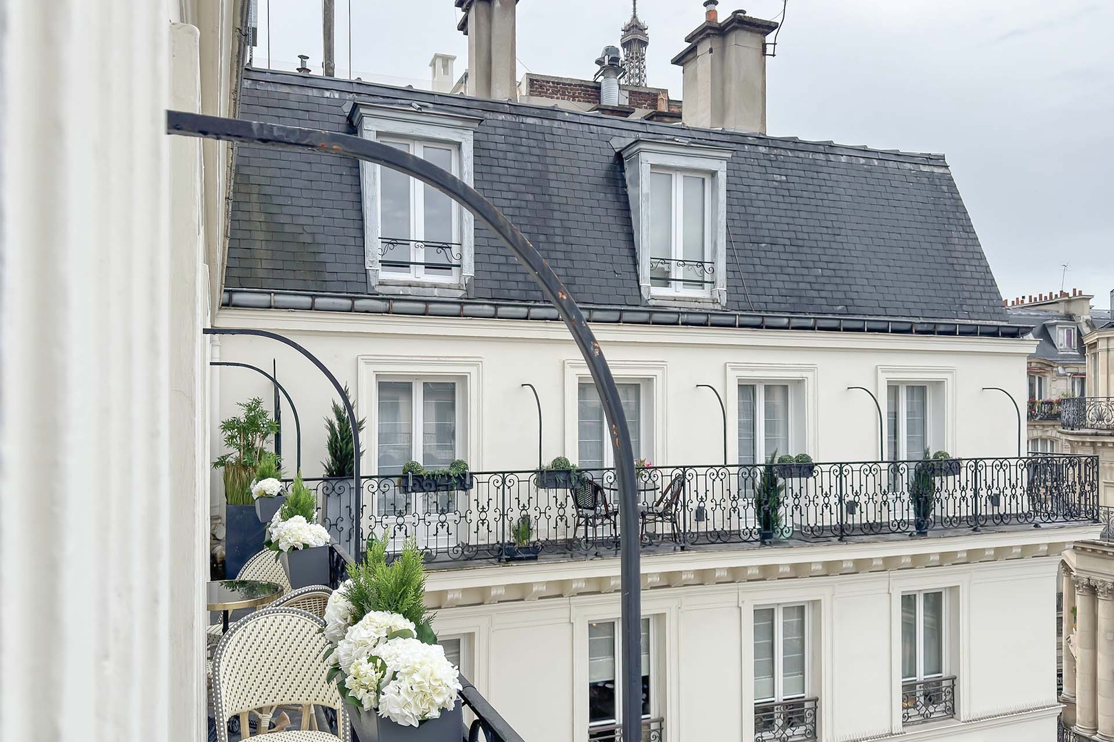 Lovely long balcony with bistro tables and glimpse of the Eiffel Tower.