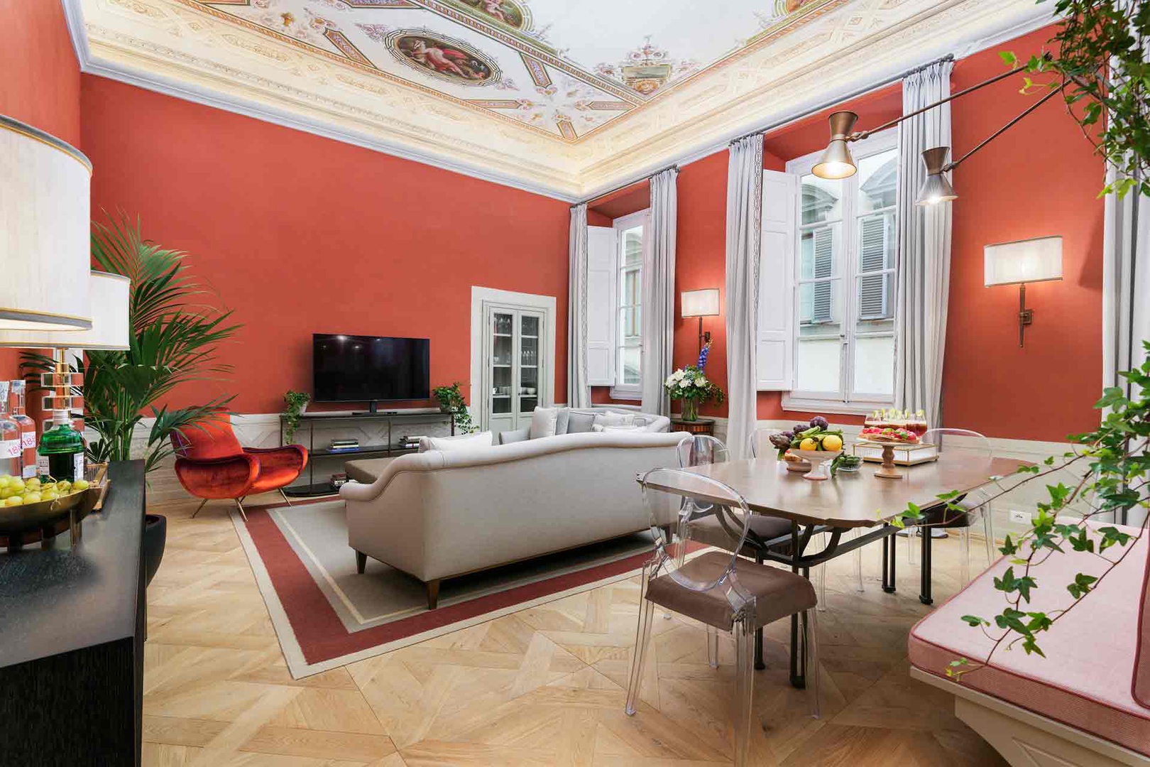 Grand living space with frescoed ceilings, tall windows flooding the room with light.
