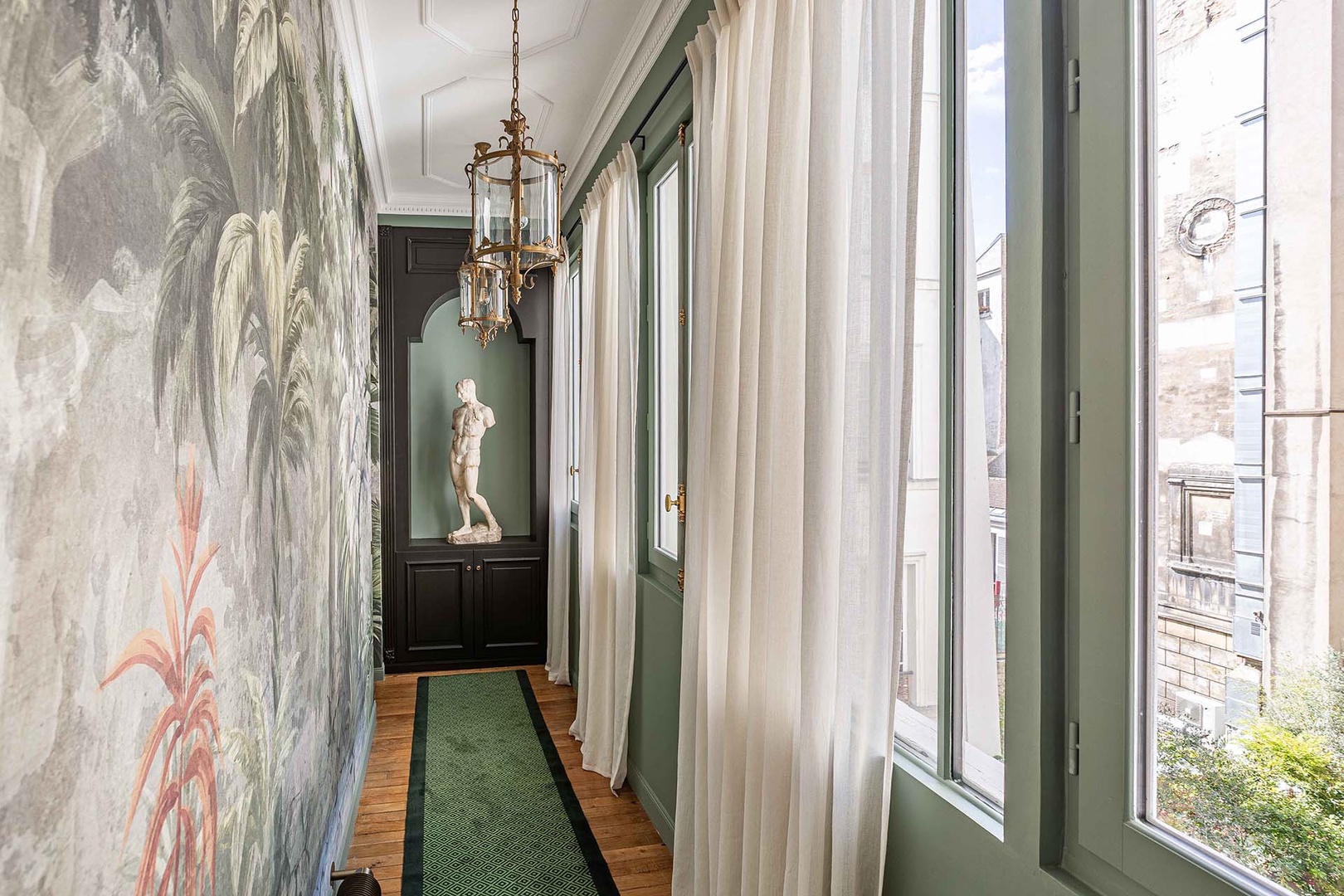 Window-lined corridor leads to den.