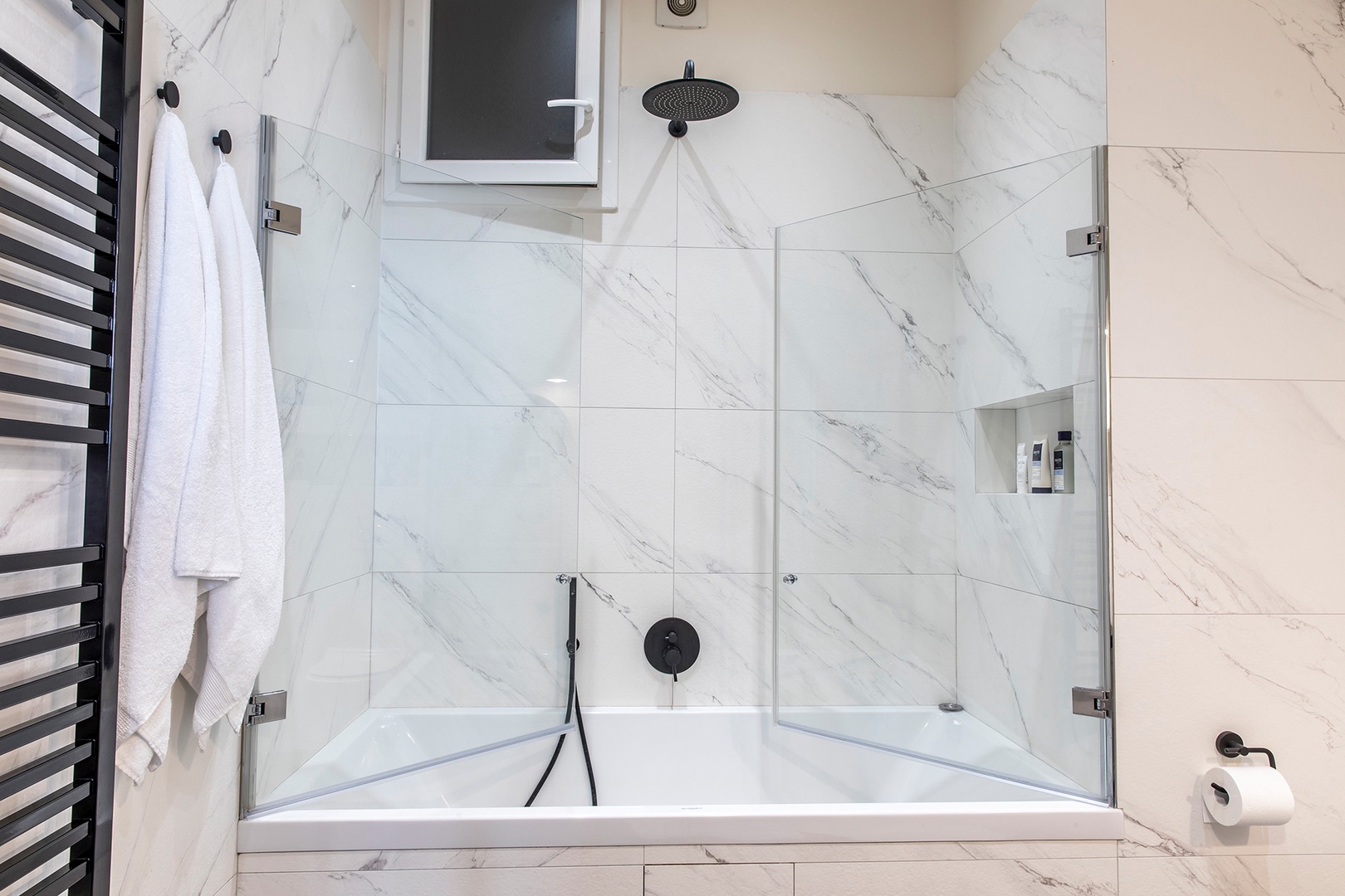 Glass enclosed bathtub also features rainwater showerhead.