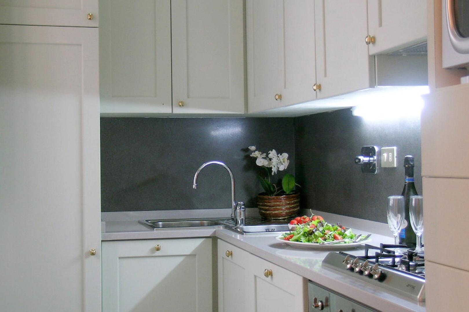 A modern kitchen glistens with microwave, oven, four burner stovetop and dishwasher.