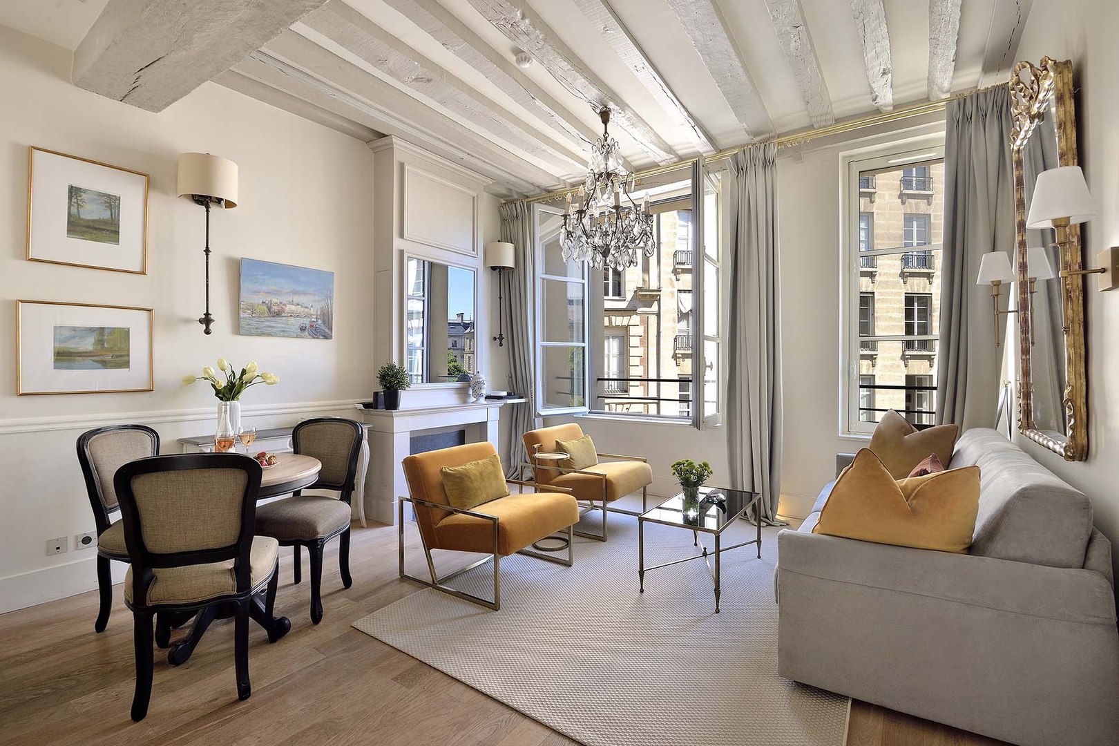 Enjoy views of Place Dauphine from the elegant sofa or dining area.