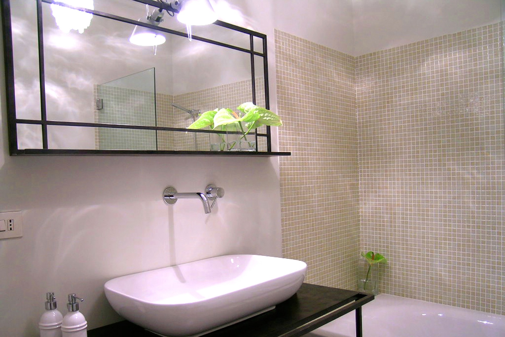 Pale sage colored tiles line the large bathtub walls of the en suite bathroom of bedroom 1.
