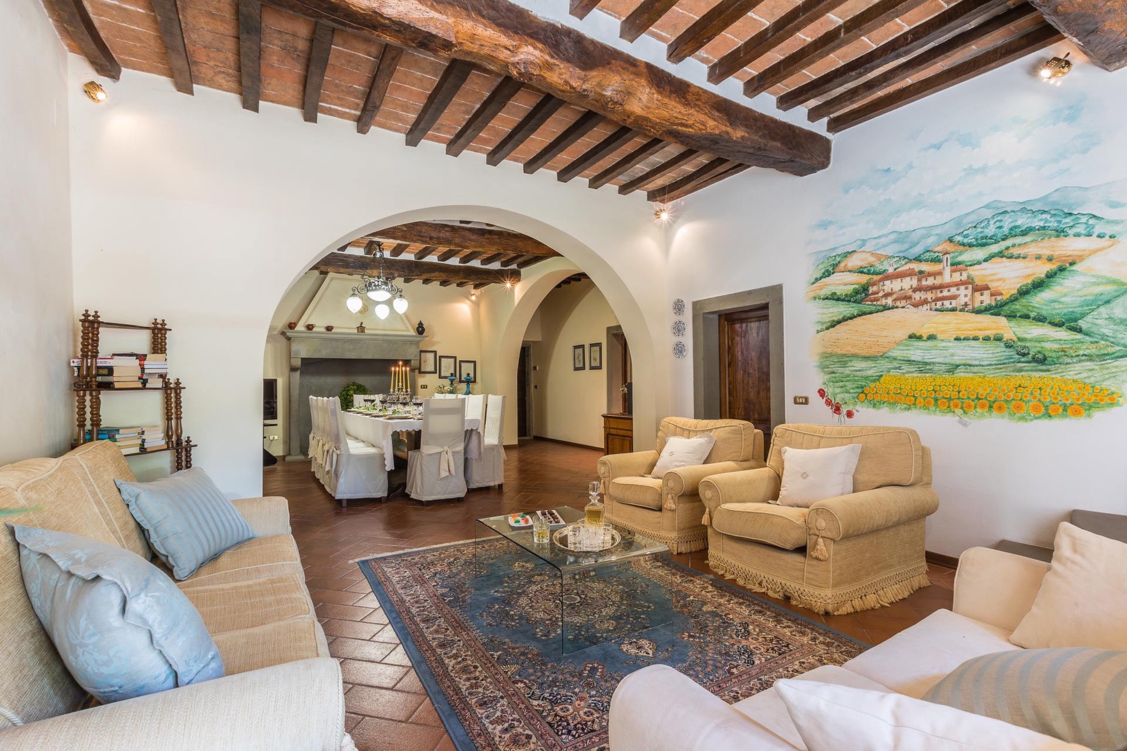Comfortably furnished living room with beamed ceilings and terra cotta tile floors.