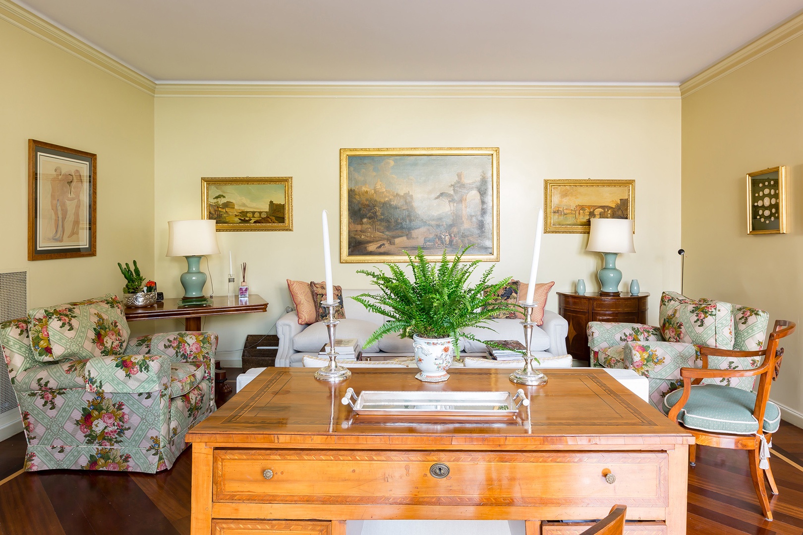 Fine oil paintings of Rome and the Roman countryside decorate the walls of the sunny living room.