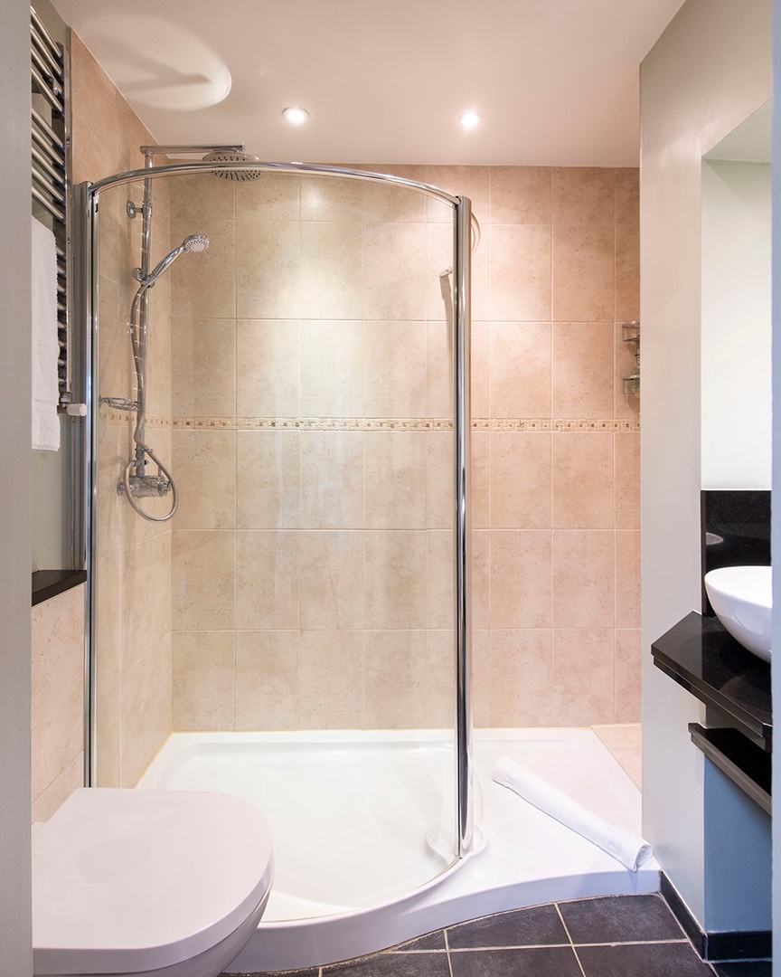 Large walk-in shower with curved glass.
