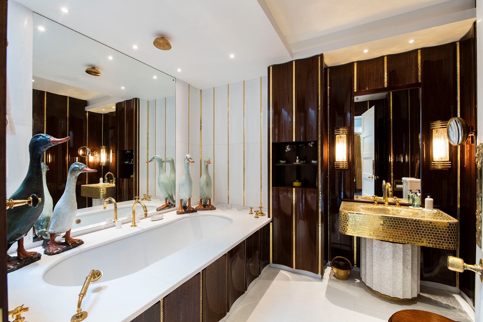 En suite bathroom in bedroom 1 with wood paneling and gold mosaic details.