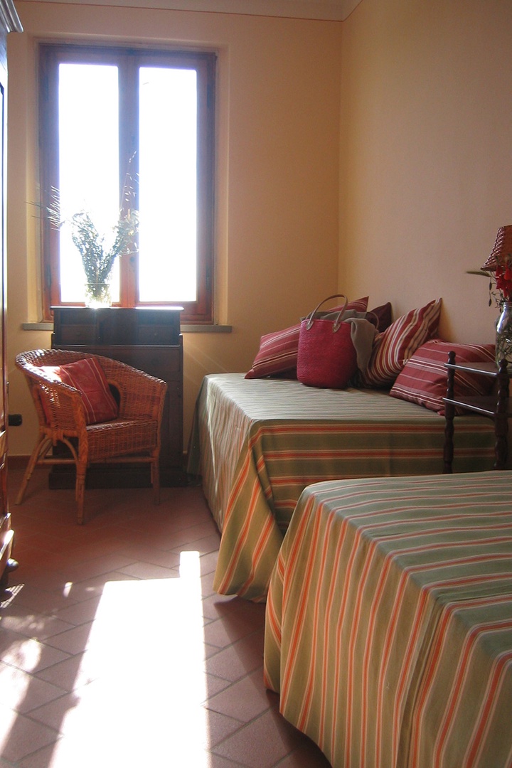 Cheerful bedroom 3 with two beds and antique armoire.