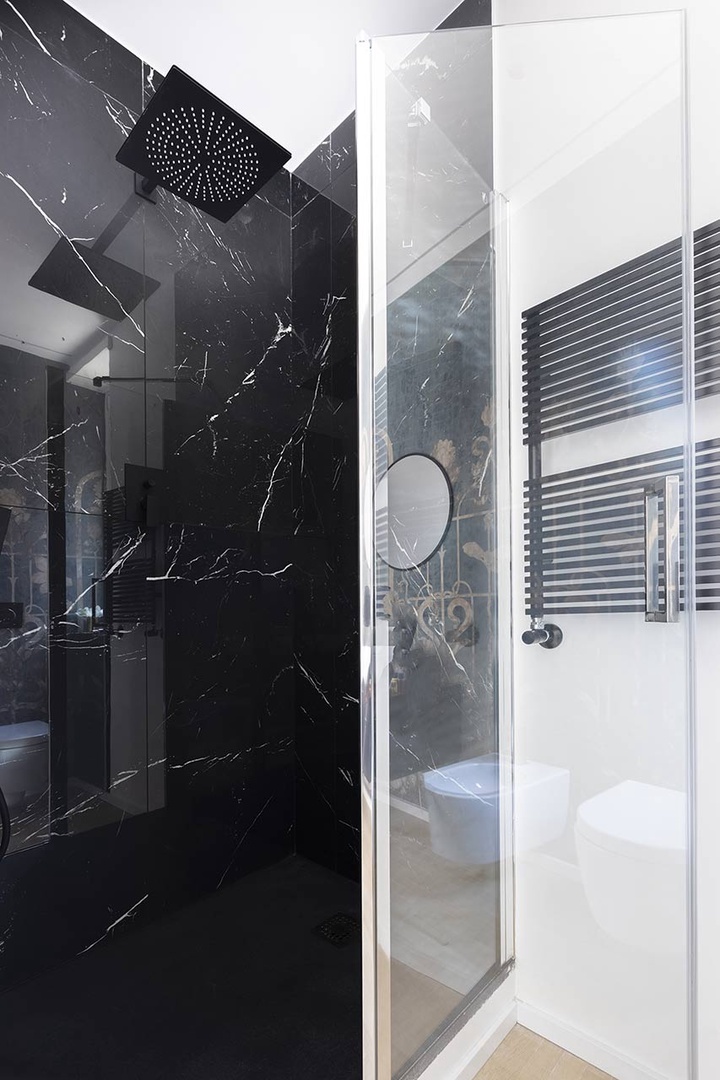 Bathroom 1 with black marble fixtures is en suite to bedroom 1.