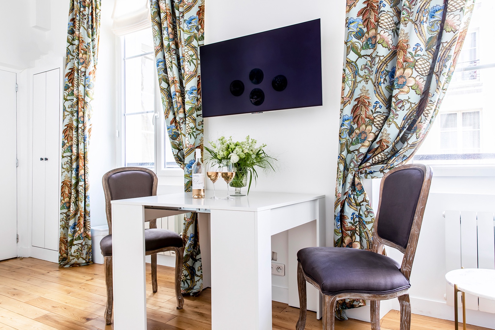 Dining table sits below a wall-mounted TV in living area.