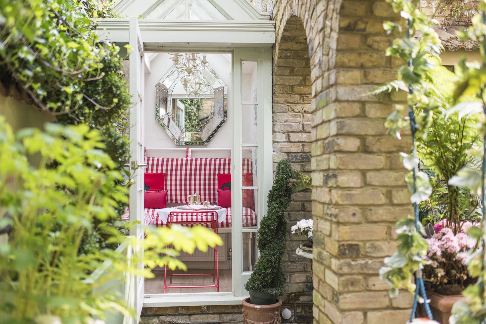 The door to the garden looks directly onto the delightful glass conservatory with chairs and table