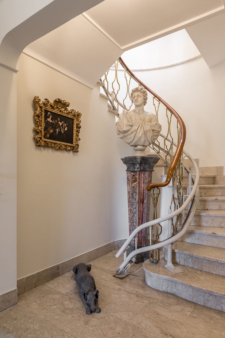 Sweeping staircase has electric chair lift for mobility-impaired.