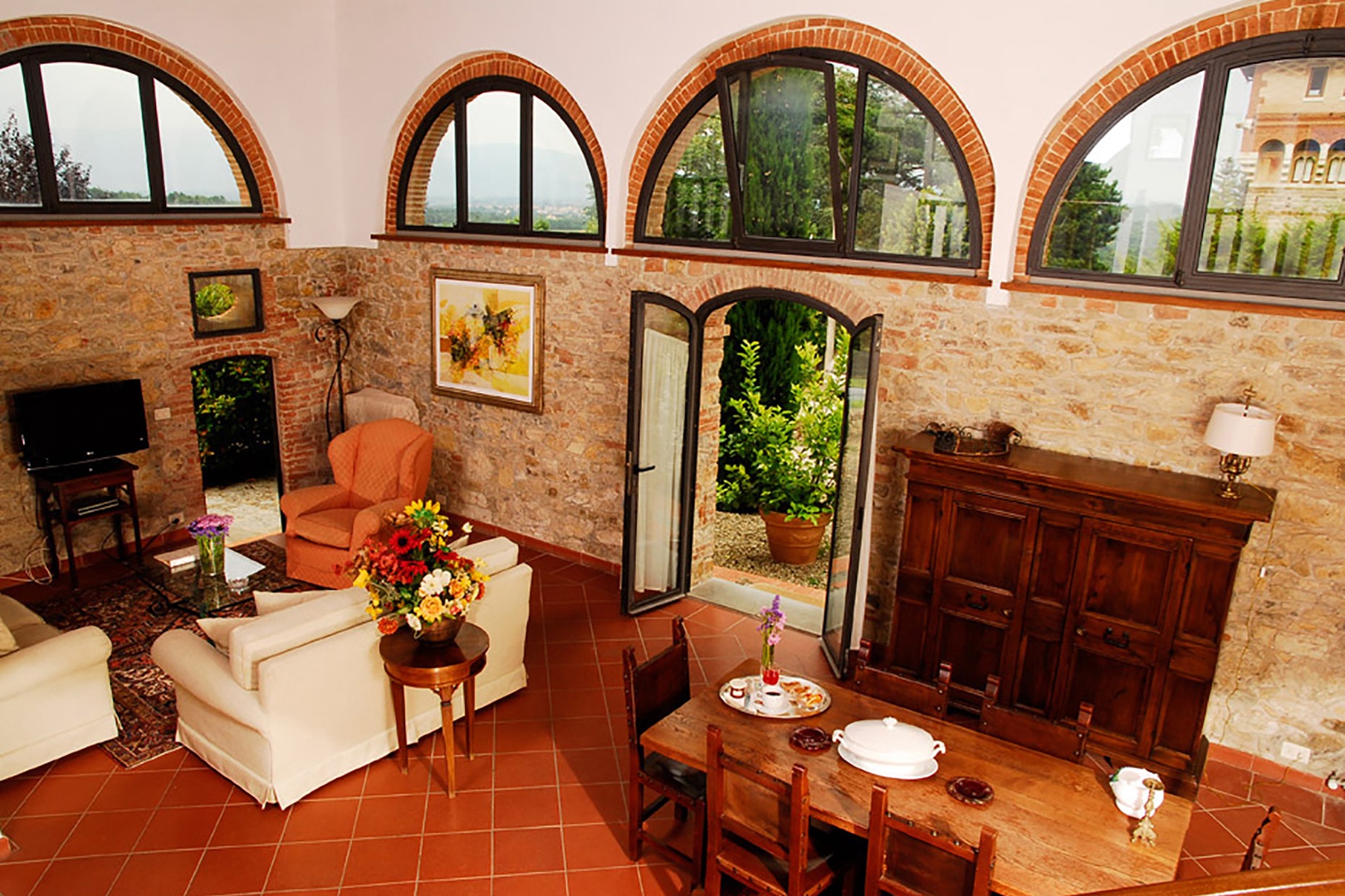 The high-ceilinged living room is filled with light from the arched windows on three sides.