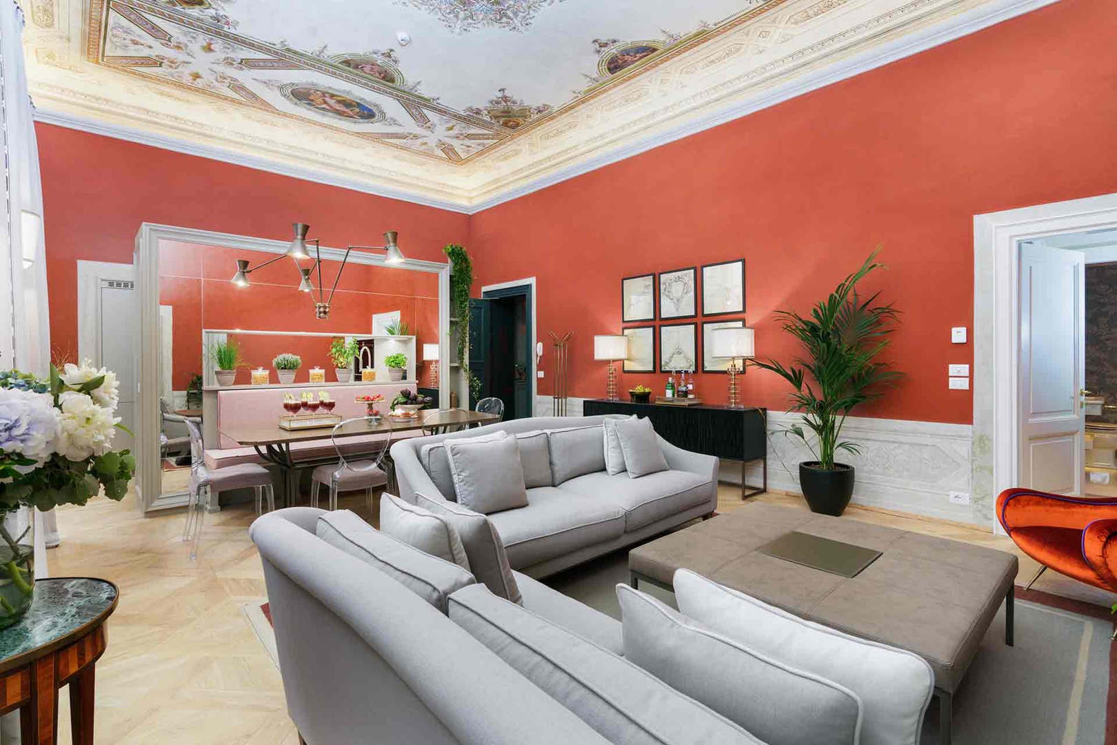 Unwind in the spacious living room where vibrant coral walls meet stunning frescoed ceilings.