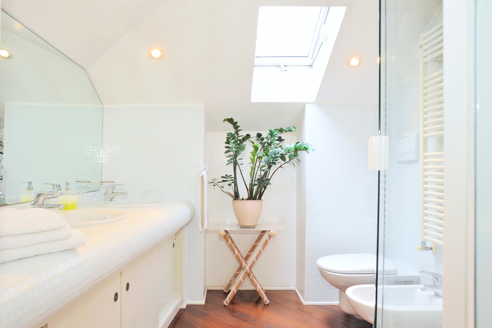 The compact bathroom with a double sink and a skylight that brightens.