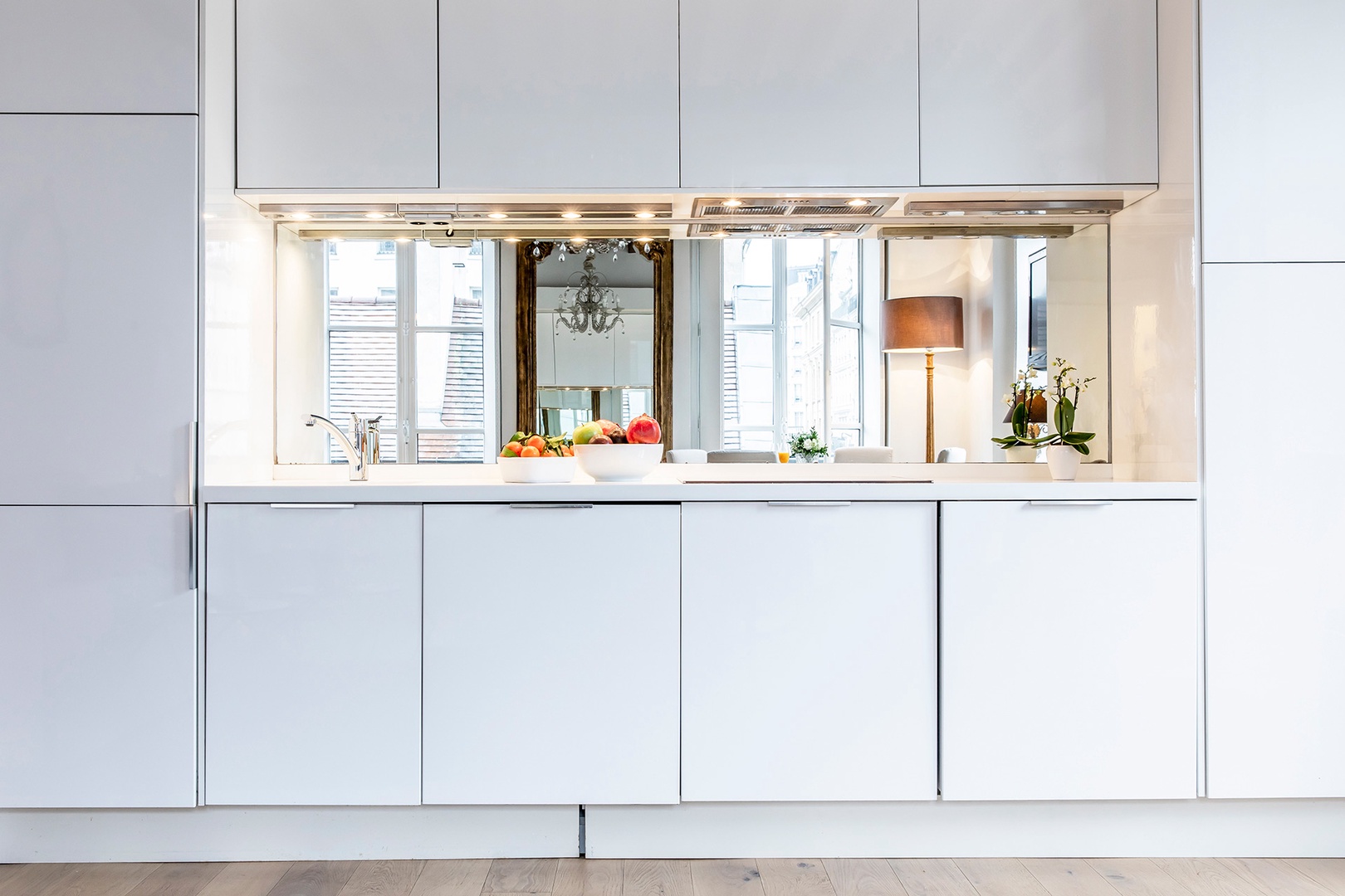 Modern kitchen with mirror creates a spacious setting.