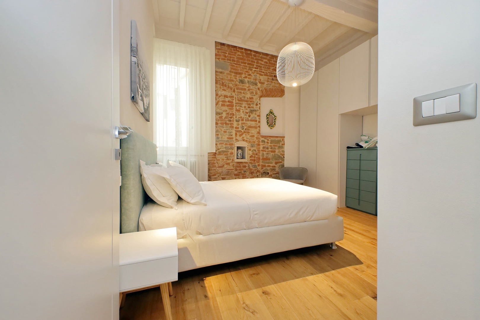 Exposed brick wall accents the bedroom beautifully.