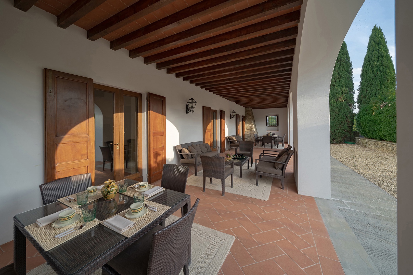 Shaded outdoor loggia with lounge chairs and outdoor dining.