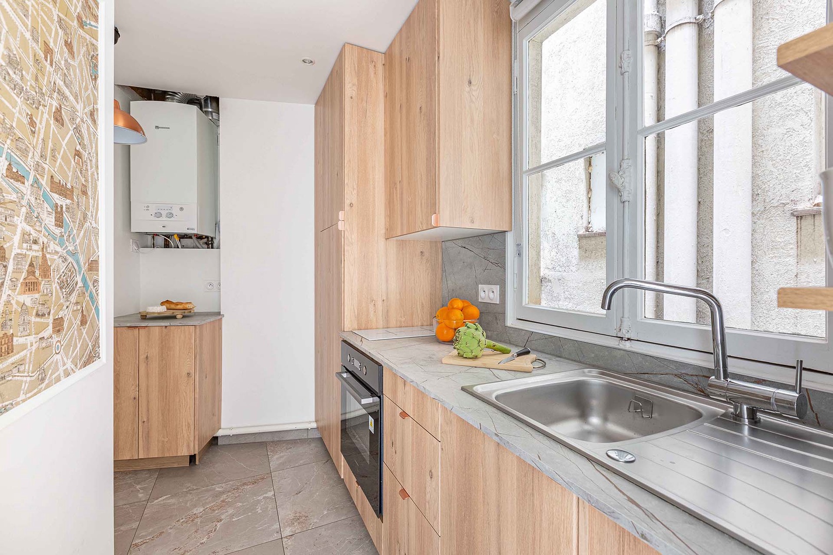 Fully equipped kitchen with light wood and large window.