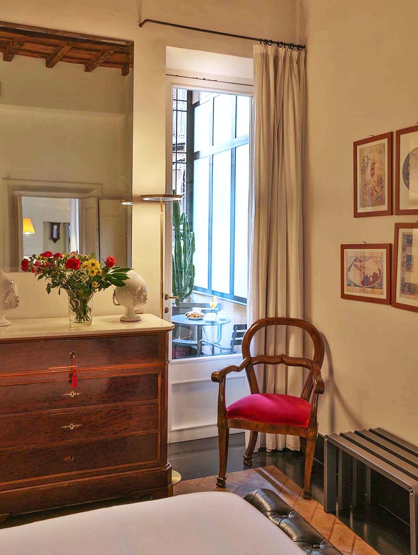 Step into your charming bedroom where antique furnishings and fresh flowers create a romantic atmosphere for your Italian getaway.