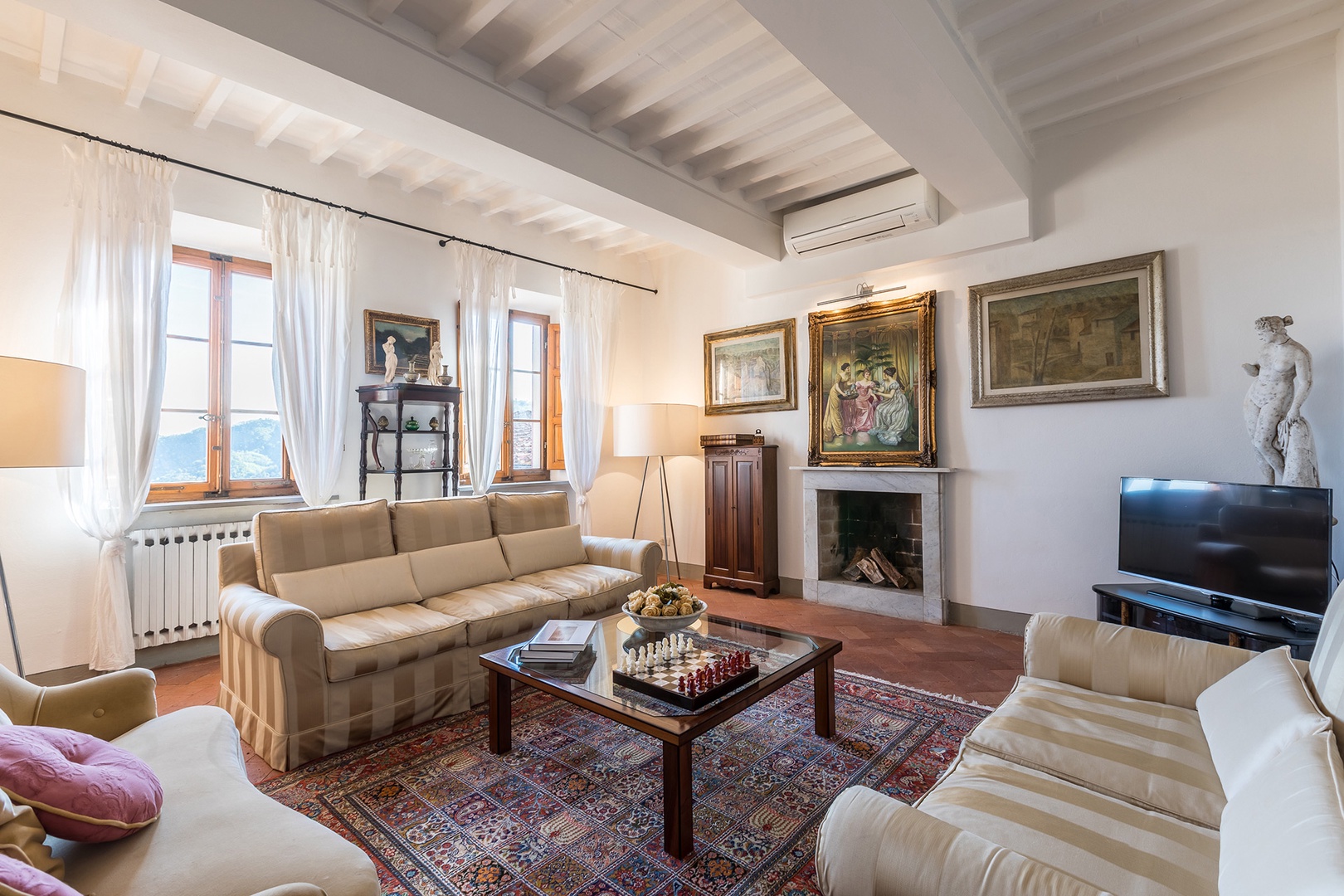 Comfortable living room with three sofas & TV.