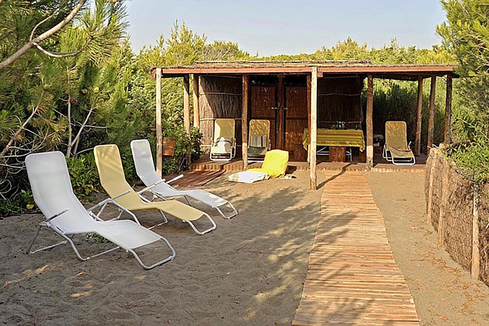 Private beach cabana with table, chairs, lounge chairs and a shower.