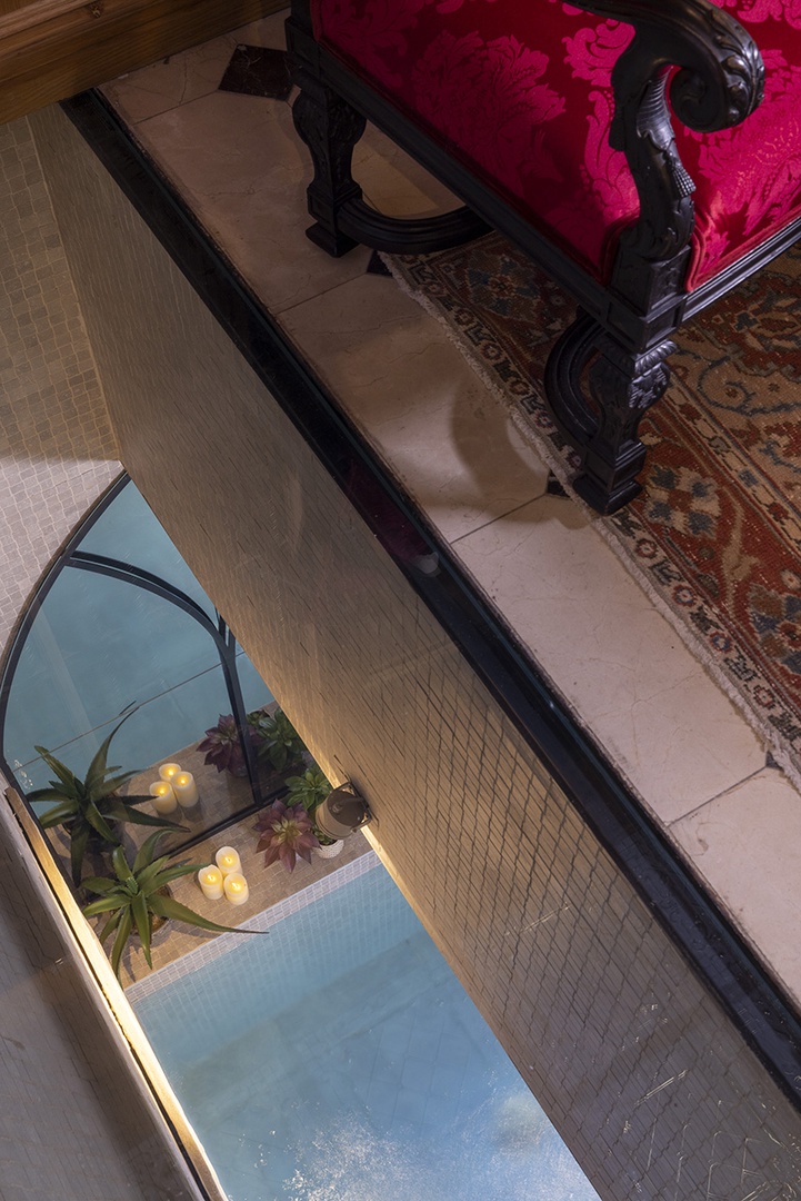 A glass panel in the living room looks down into the pool on lower level.