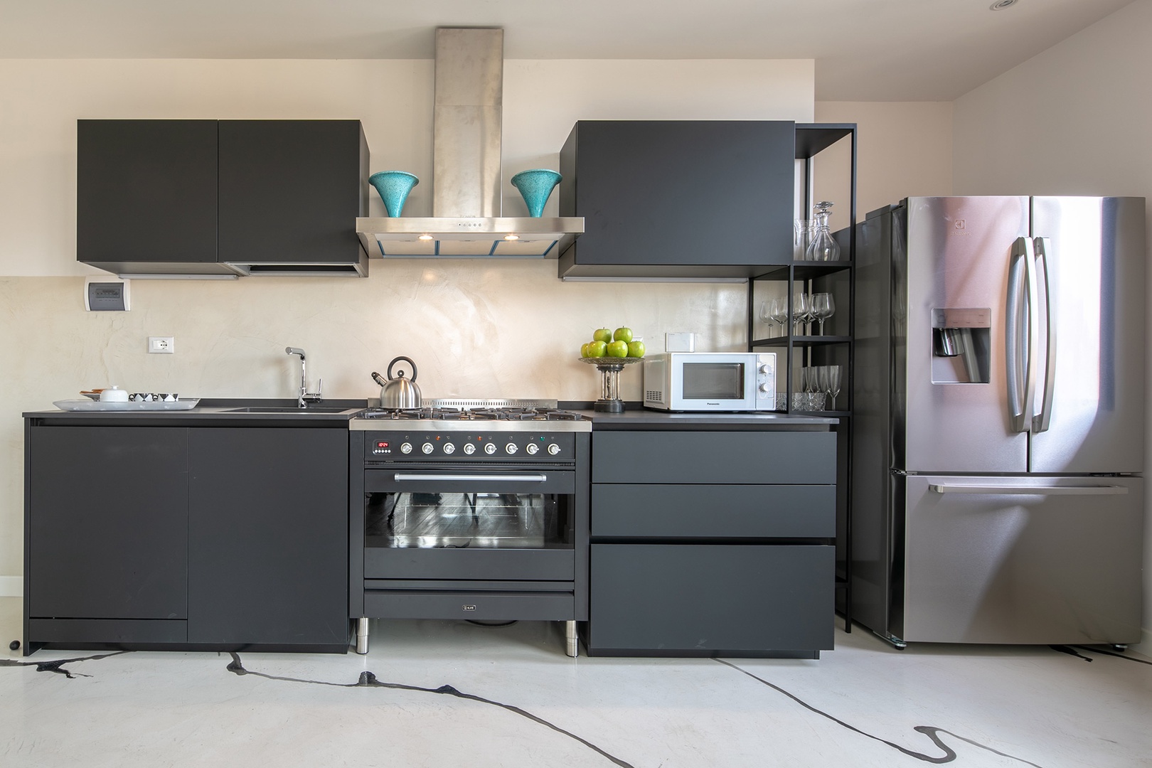 Bright modern kitchen with full-size refrigerator and six-burner stove.