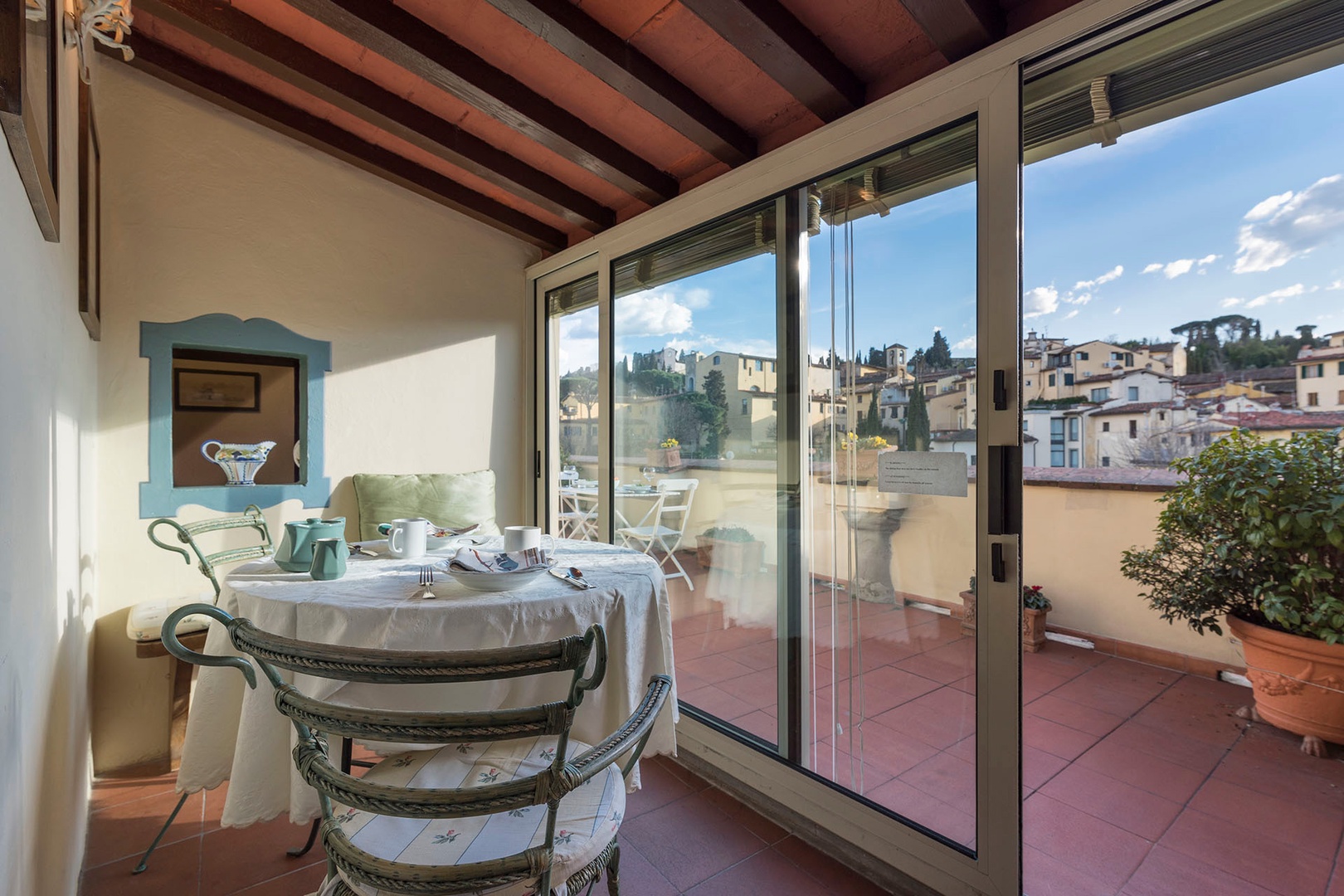 Glass enclosed sun room has a dining table with seating for 2 and views out the terrace.