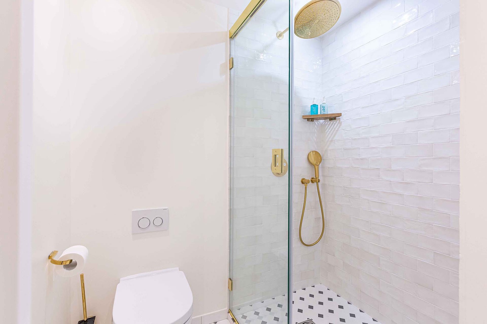 Bathroom 2 is a sleek, modern bathroom with elegant gold fixtures .