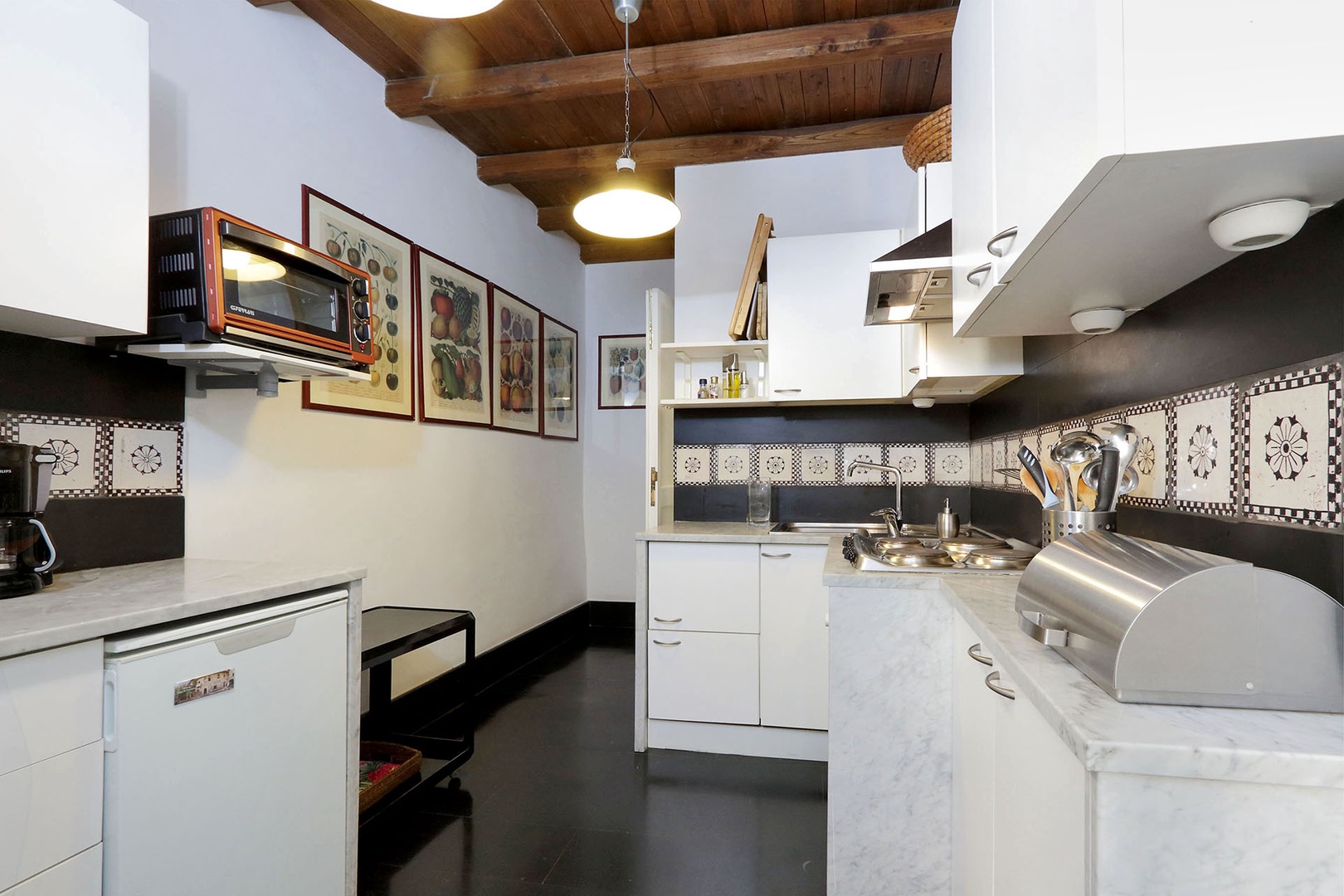 Colorful prints on the first kitchen walls are echoed in the antique Italian tiles that line the walls