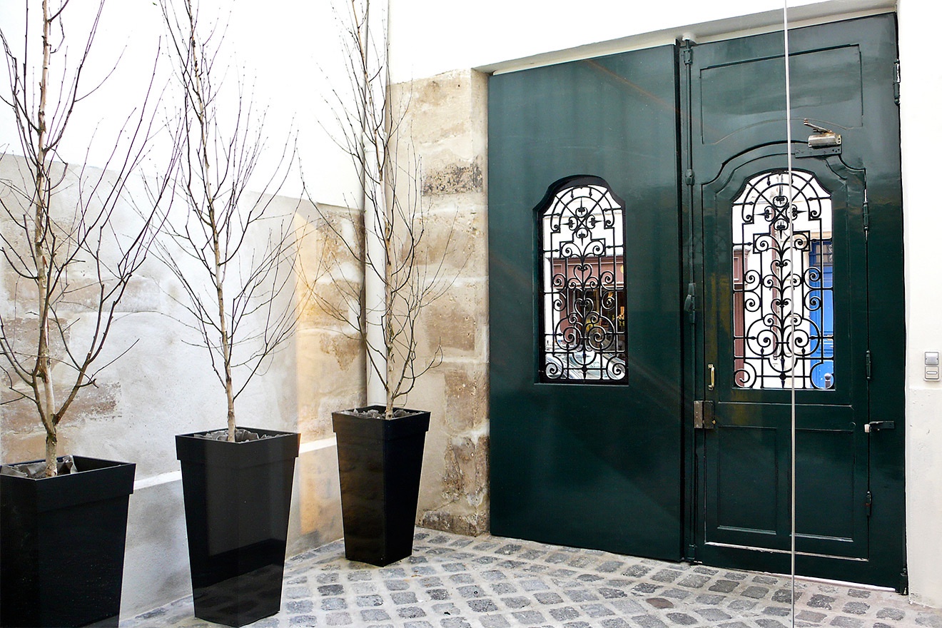 Enter through old wooden doors to a cobblestone courtyard.