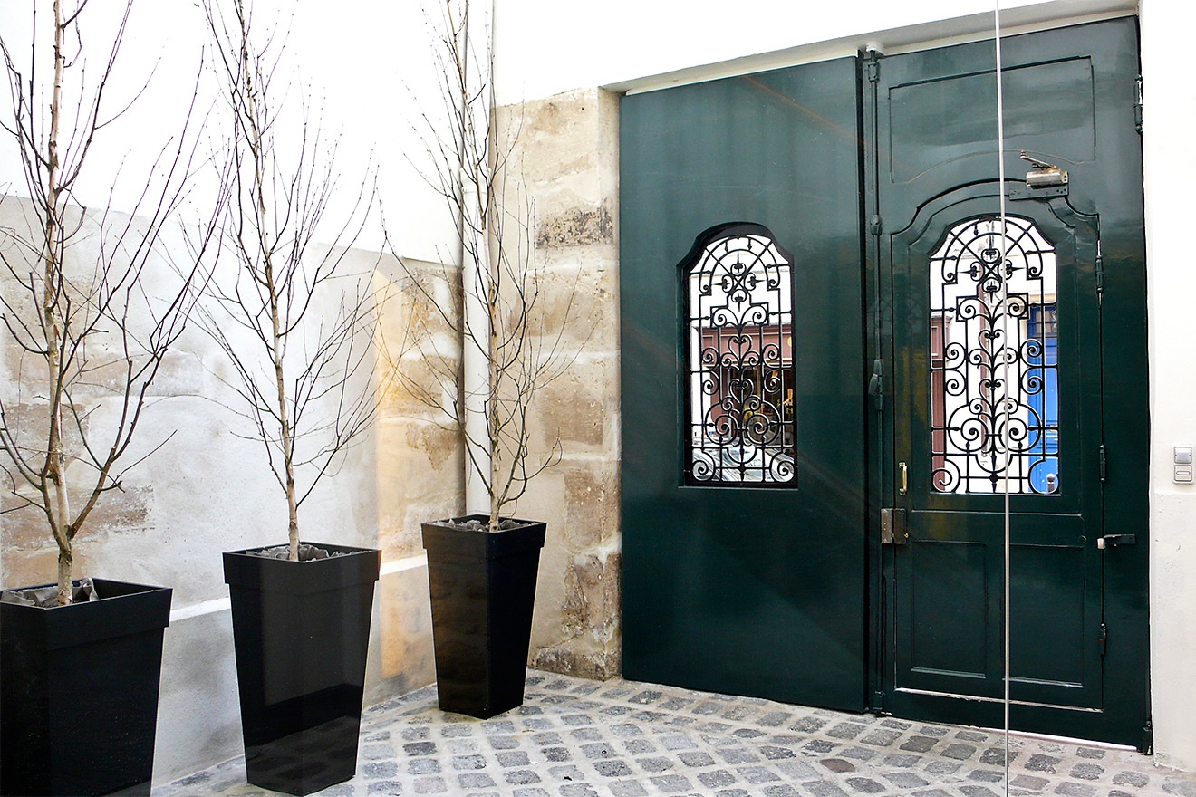 Enter through wooden doors to a cobblestone courtyard.