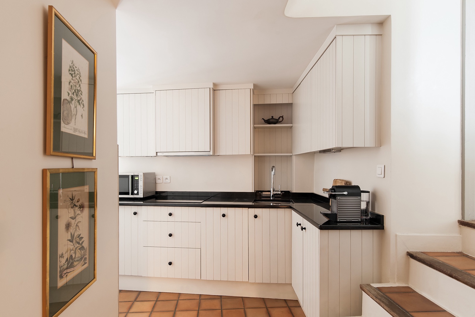 Steps lead down to the stylish black and white kitchen.