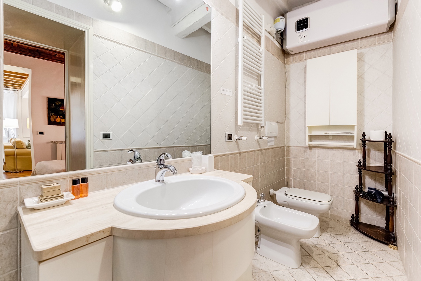 Compact bathroom has shower stall, washing machine, sink, toilet and bidet, heated towel rack.