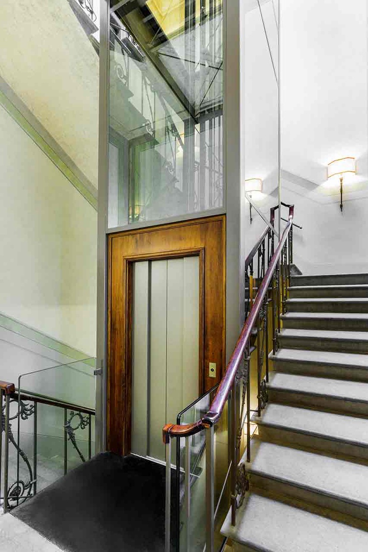 Glass-paneled elevator provides easy access between floors, with staircase offering an alternative route..