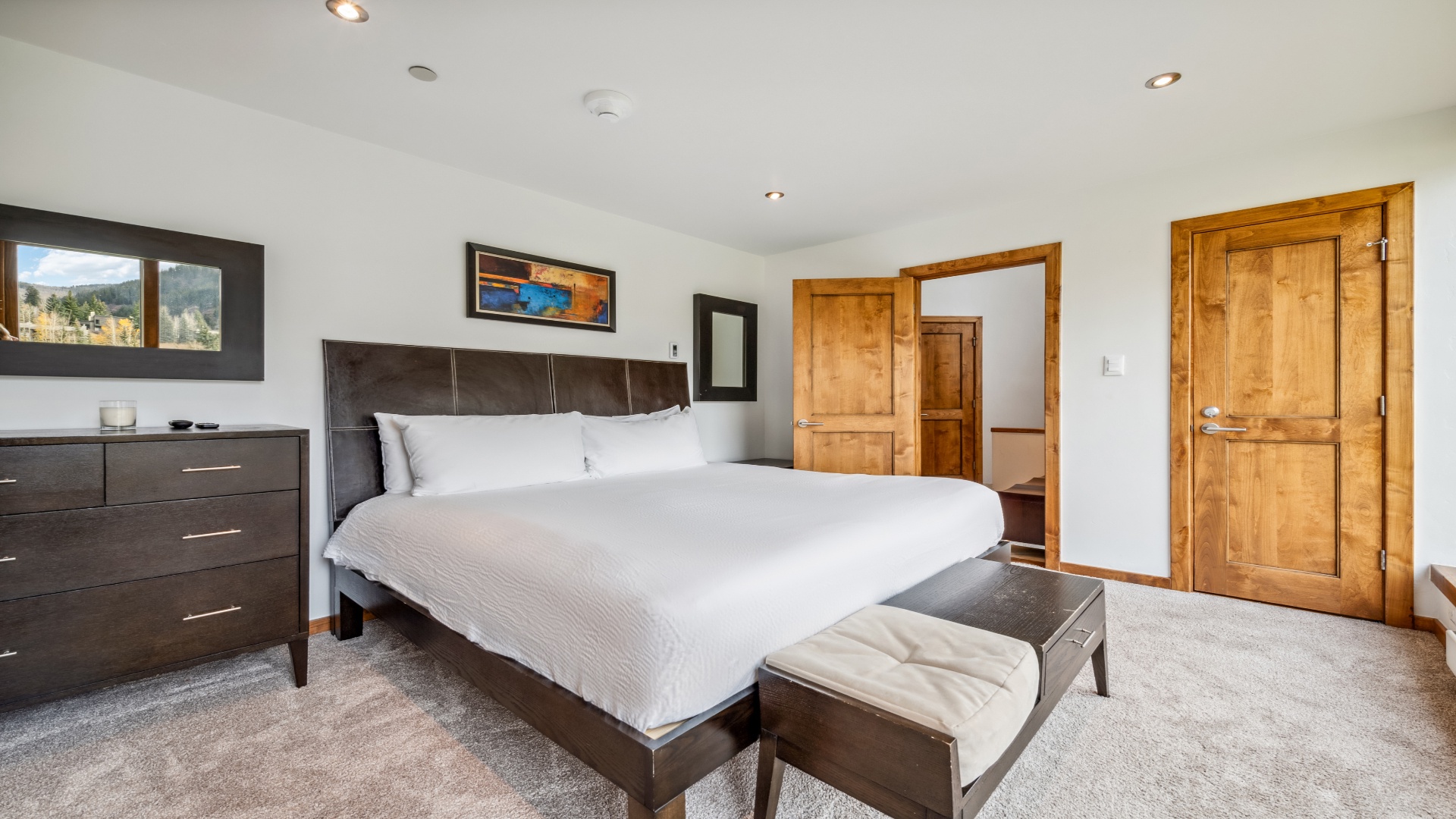 Sink into crisp linens and restful sleep in this modern bedroom, where plush carpeting, stylish furnishings, and scenic mountain views create your perfect mountain retreat.