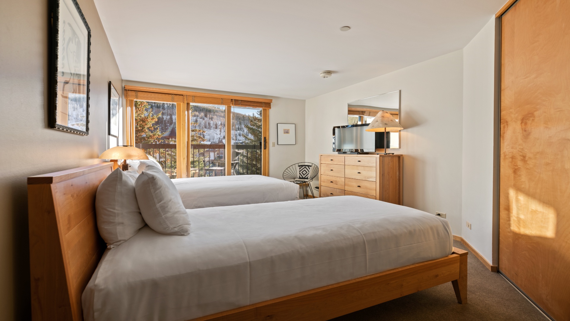 Settle into your serene bedroom suite where natural light fills the space and mountain views greet you each morning through elegant wood-framed windows.