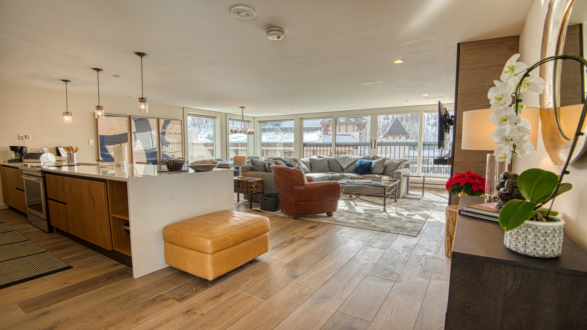 Step into your inviting open-concept living space where warm wood floors and stylish modern furnishings create a perfect retreat. Natural light floods through expansive windows, framing peaceful views while you relax in comfort.