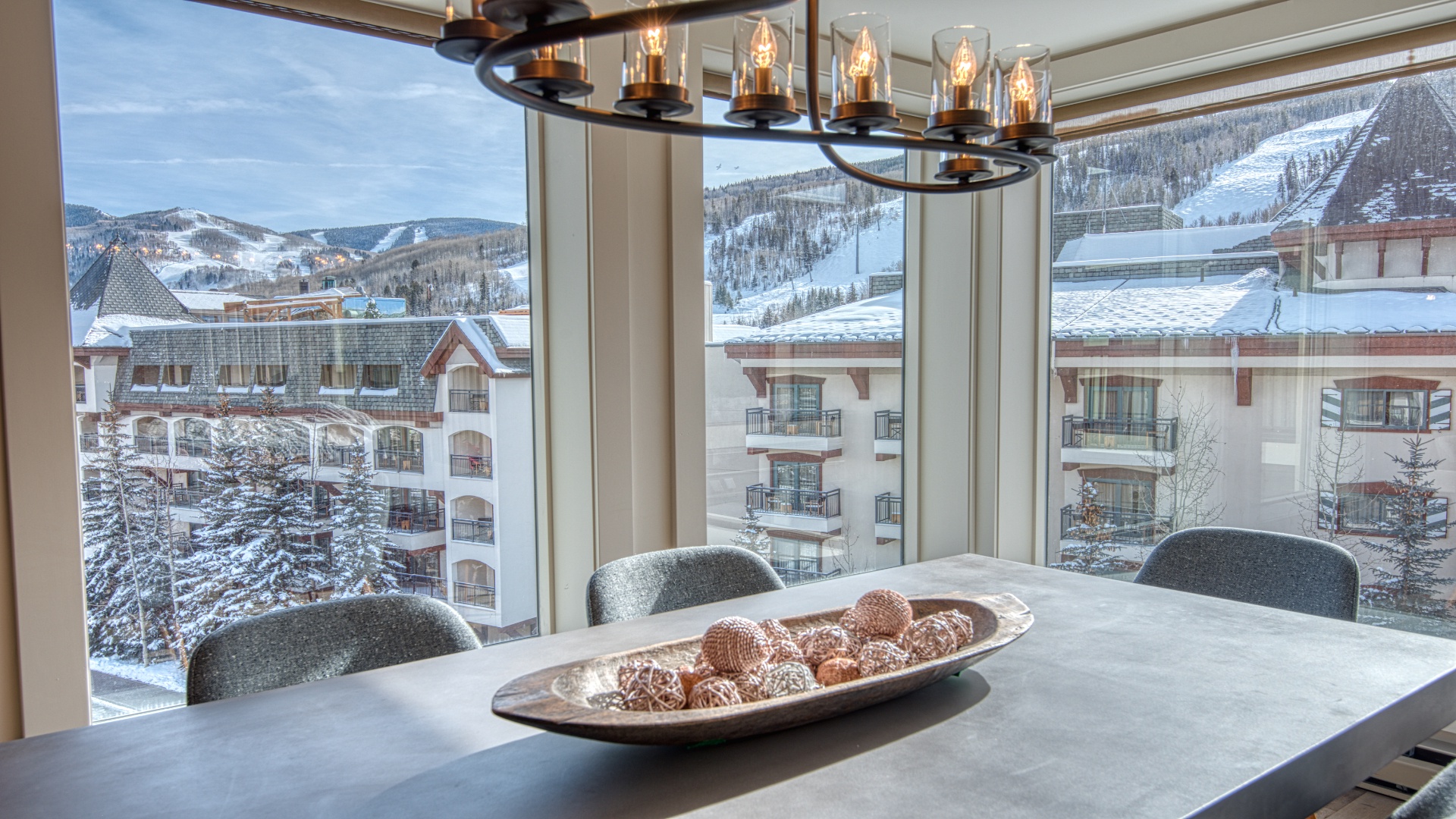 Picture yourself at this table, savoring morning coffee while taking in sweeping winter mountain views and the charming alpine village below—your perfect mountain escape.