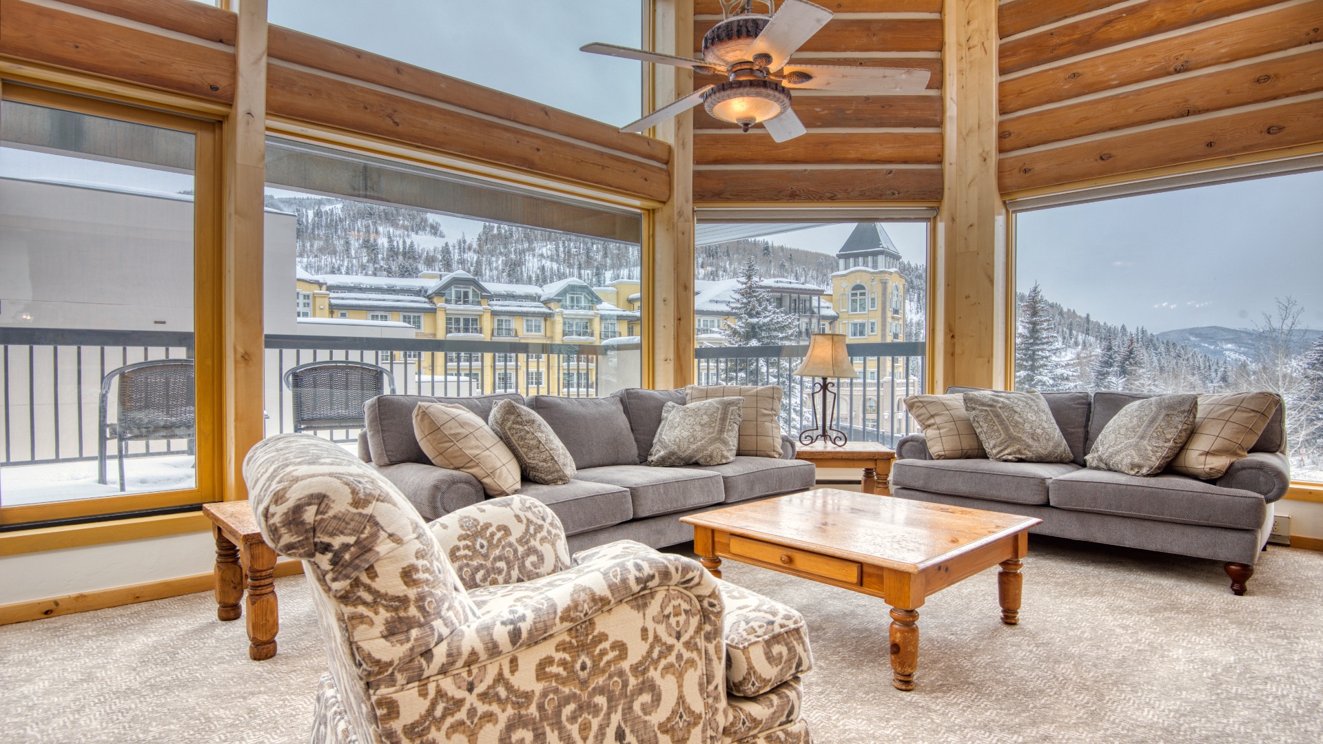Sink into plush seating in your vaulted living room, where floor-to-ceiling windows frame stunning winter mountain vistas and cozy wood beams create a warm alpine retreat.