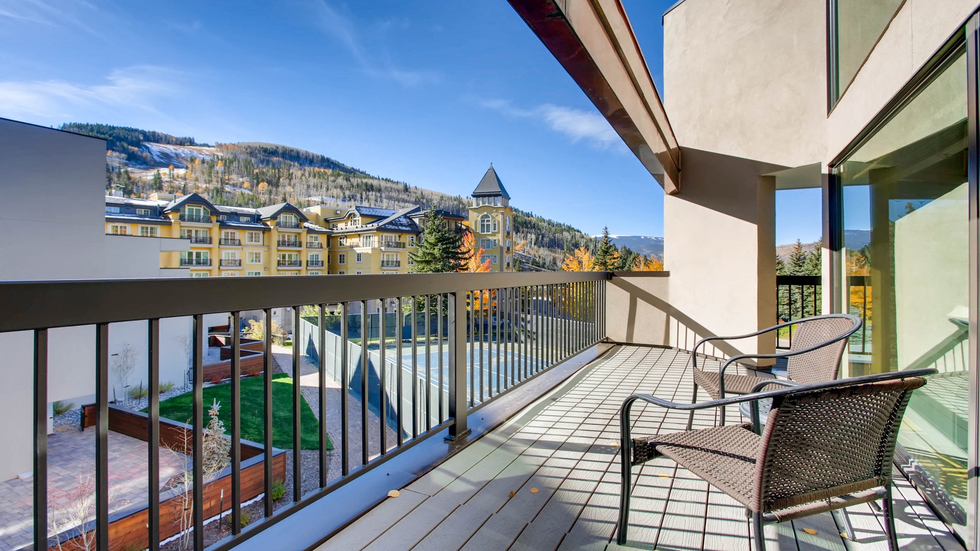 The balcony frames stunning mountain and village views—perfect for morning coffee or après-ski relaxation. Two chairs invite you to unwind and soak in the alpine scenery.