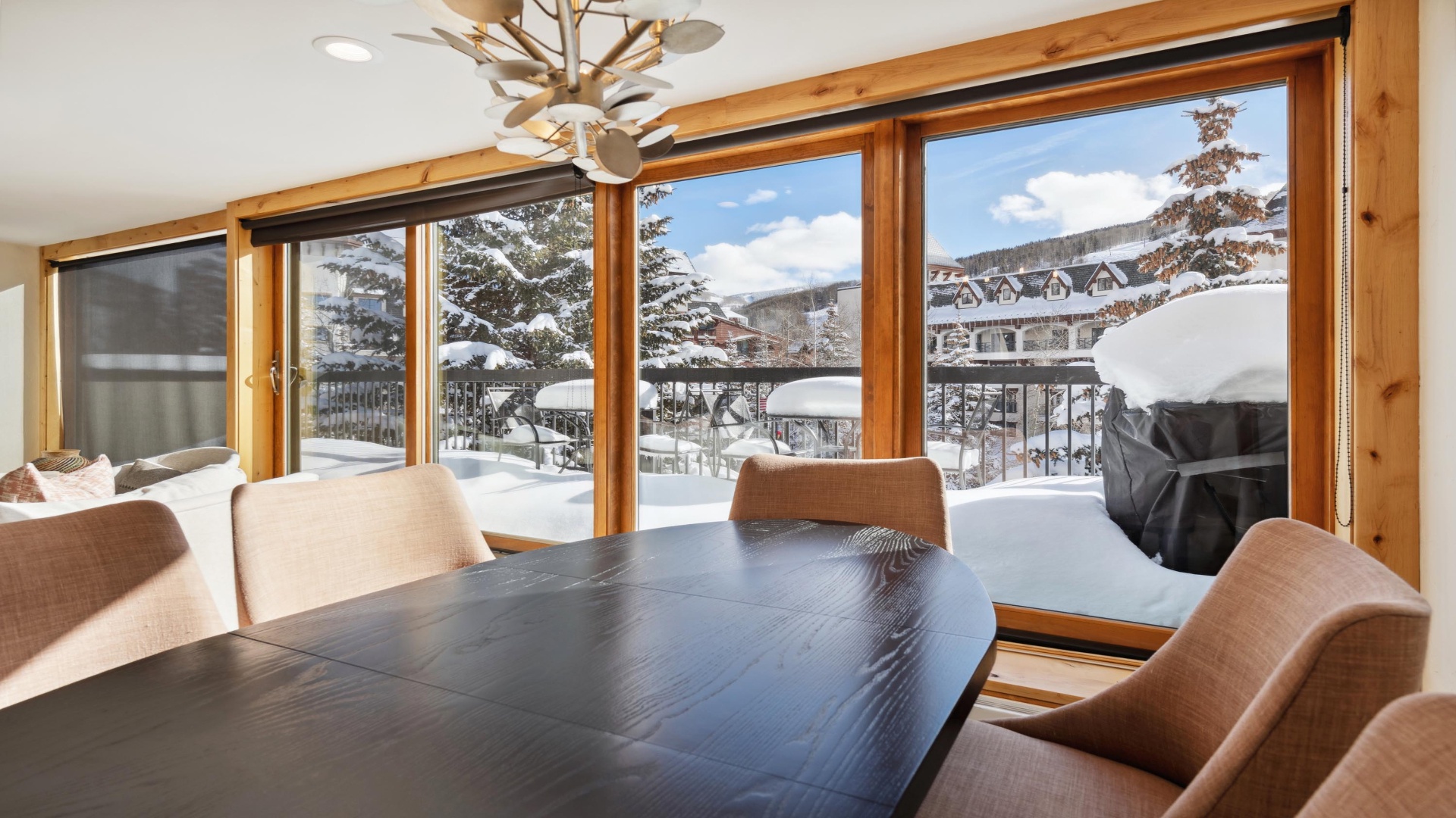 Gather around this inviting dining table and enjoy panoramic winter views through floor-to-ceiling windows. The warm wood tones and cozy seating create the perfect spot for your morning coffee or family meals.