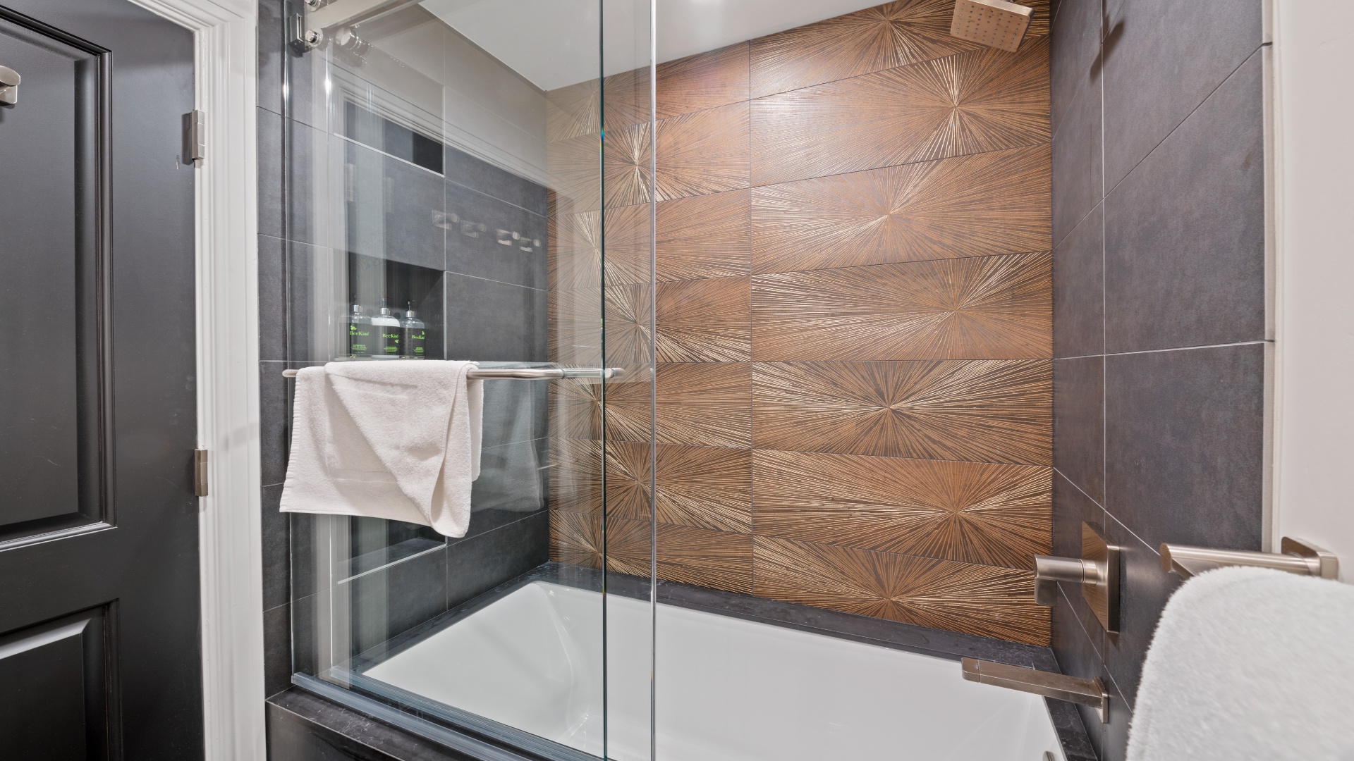 Step into your private spa-like retreat with a spacious walk-in shower featuring stunning wood-textured accent tiles and sleek modern finishes that invite relaxation.