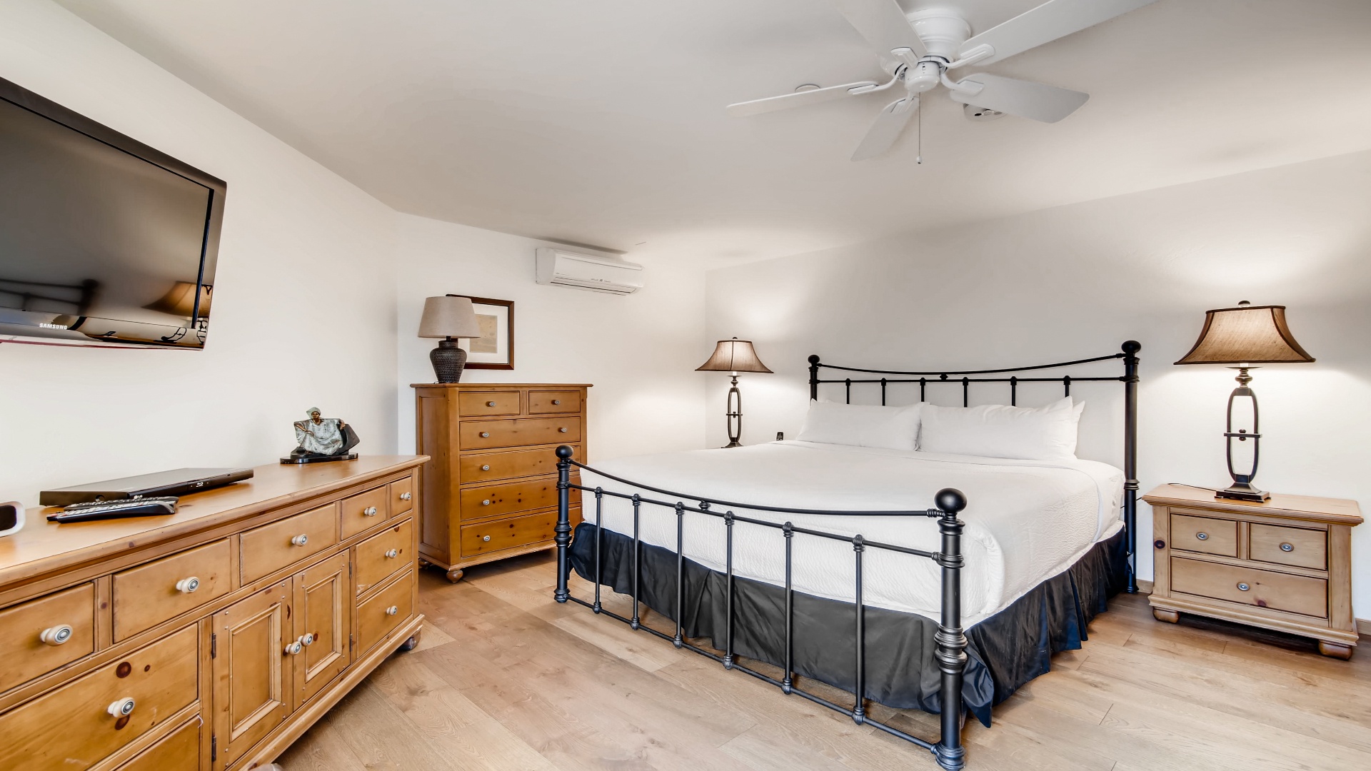 Your spacious bedroom features a plush king bed, warm wood furnishings, and ceiling fan to keep you comfortable. Enjoy your favorite shows on the mounted TV before drifting off.
