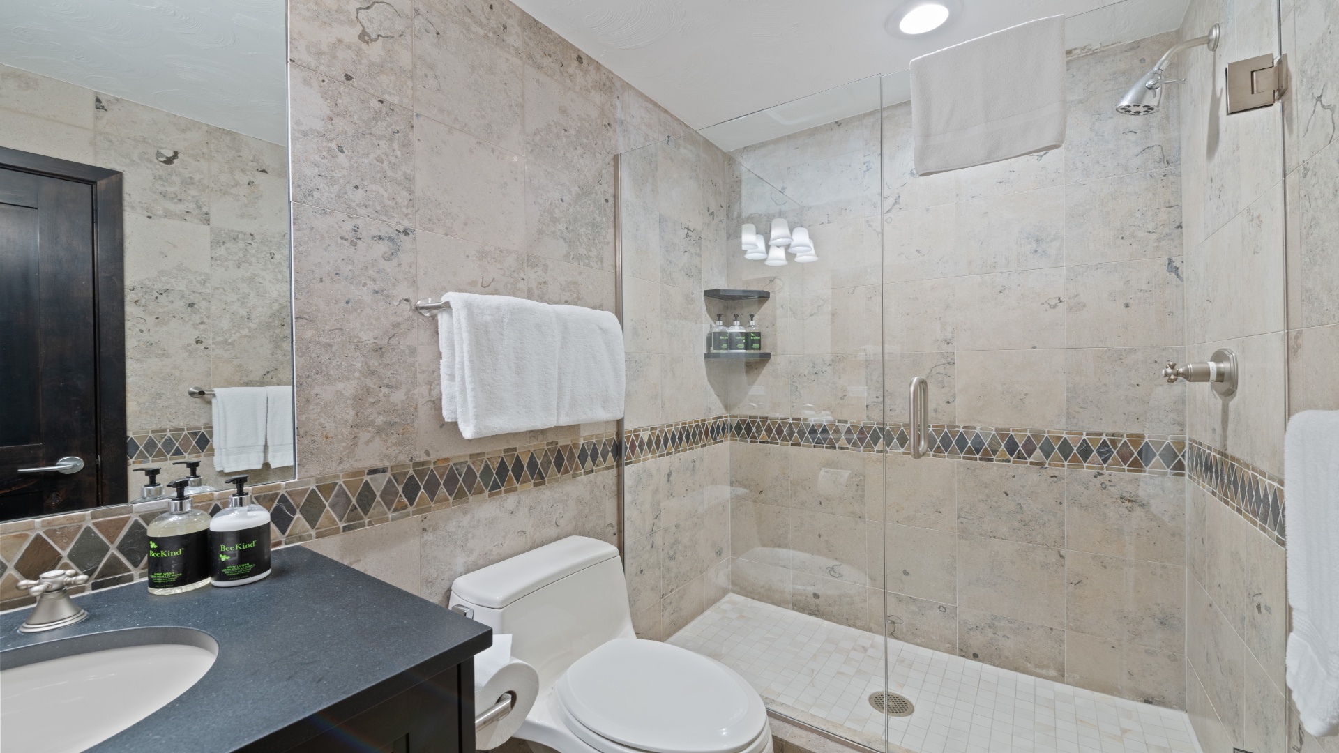 Unwind in your beautifully tiled bathroom featuring a spacious walk-in shower with modern fixtures, plush towels, and thoughtful amenities to refresh after your adventures.